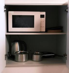 a microwave oven above two pots and pans on a shelf at Unwadang Private Luxury Hanok House in bukchon in Seoul