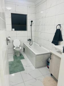 a white bathroom with a toilet and a tub and a tv at KT Comfort in Midrand