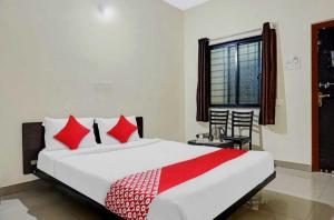 a bedroom with a bed with red pillows and a window at Super Hotel O Sai inn 2 in Pune