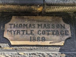 a stone sign on the side of a building at Myrtle Cottage Findhorn in Forres