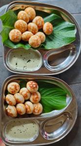two trays of food with shrimp and green leaves at Vinayaka Homestay Hampi in Hampi