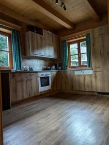Una cocina vacía con pisos de madera y ventanas en una cabaña. en Schindlhaus, en Grossarl