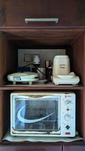 a microwave in a wooden cabinet with aperature at Madu's Mountain View Home in Badureliya