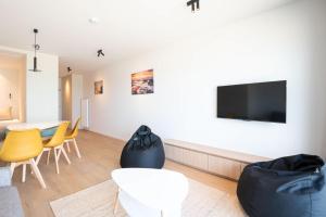 a living room with a tv and a table and chairs at Luxurious studio with a stunning view in Middelkerke