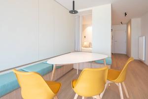 a dining room with a white table and yellow chairs at Luxurious studio with a stunning view in Middelkerke