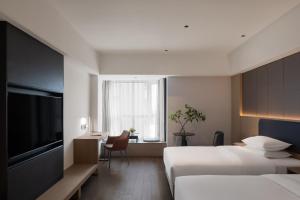 郑州新郑国际机场BlueVisual Hotel Zhengzhou Airport的有两张床和一台电视的酒店房间