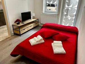 ウーディネにあるLuxury Allo Apartment in center of Udineのベッドルーム1室(赤いベッド1台、タオル付)