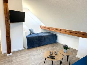 a small living room with a bed and a table at LGH-Moderne, ruhige Wohnung, Nähe zum Flughafen und Autobahn, 24h-self-check-in, vollausgestattet, DisneyPlus, Waschmaschine in Langenhagen +12 photos