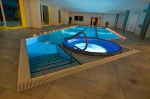 a large swimming pool with a large blue tub at Hotel Weingarten in Caldaro