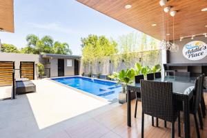an outdoor dining area with a swimming pool and a table and chairs at Addie's Place Soldiers Hills Village Muntinlupa in Manila