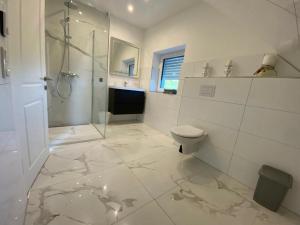 a white bathroom with a shower and a toilet at Neubau Luxusanlage Gesamte Haus in Buckhorn