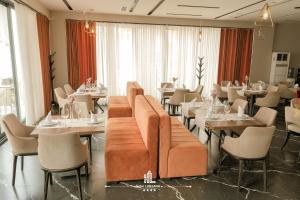 a restaurant with tables and chairs and a couch at Dolanit Hotels Lubjana in Durrës