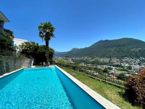 una piscina con una palma e una città di The Lemon Trees House a Lugano