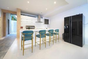 a kitchen with blue bar stools and a black refrigerator at Surf Beach House Pool Villa in Na Jomtien
