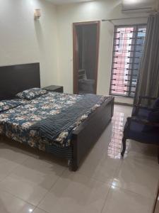 a bedroom with a bed and a chair and a window at Doctor's house in Lahore