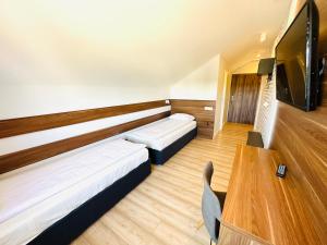 DębnoにあるAgawa restauracja&Hotelのベッド2台、テーブル、テレビが備わる客室です。