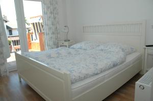 ein weißes Bett mit blauer Decke im Schlafzimmer in der Unterkunft Boardinghouse in Büsum