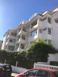 Un coche rojo aparcado delante de un edificio blanco. en Los Nidos, en Torremolinos