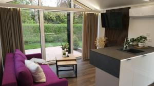 a living room with a purple couch and a kitchen at LandZeit - get your tiny moments in Sohren