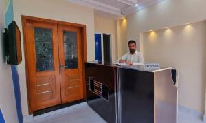 a man sitting at a counter in an office at Al Warda Hotel in Lahore