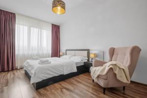 a bedroom with a bed and a chair at ArtMob Apartment Isaran in Braşov