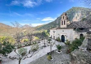 an old stone church with mountains in the background at Maison avec piscine privée in Cabra del Santo Cristo