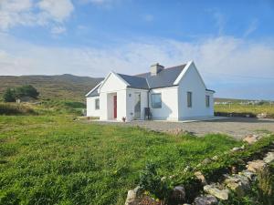 Achill Island Holiday home by the Sea - Idyllic views, Sleeps 6, Full kitchen, Fireplace and Wifi throughout في Achill Sound: بيت ابيض وسط ميدان