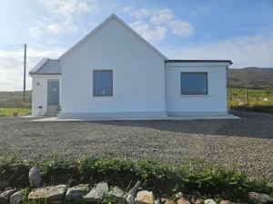 a white house with two windows on a gravel driveway at Achill Island Holiday home by the Sea in Achill Sound