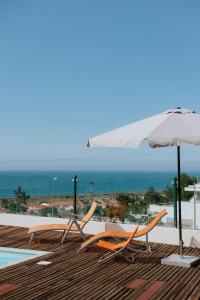 ein paar Stühle und ein Sonnenschirm auf einem Deck in der Unterkunft Casa das Camarinhas in Murtinheira