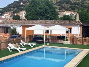 a swimming pool with two white umbrellas and chairs next to a house at Casa rural torre chica in Frailes