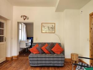 a living room with a black and white couch with orange pillows at Ferienwohnungen Hermannsmuehle in Klausdorf