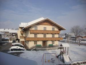 ein großes Haus mit Spielplatz im Schnee in der Unterkunft Gästehaus Schwoagerhof in Fügen