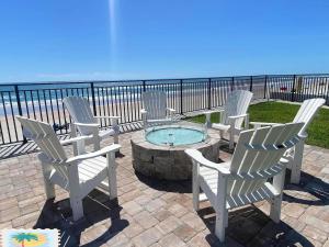 Un grupo de sillas y una fogata con la playa. en Vacation in Comfort and luxury - "THE SHERWIN" Oceanfront Condominium 906, en Daytona Beach Shores