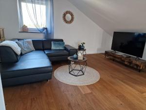 Una sala de estar con un sofá azul y un televisor de pantalla plana. en Haus im Glück, en Freigericht