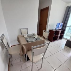 a dining room with a table and chairs and a television at Apartamento Taguatinga Sul 2 quartos com garagem elevador 1 a 4 hospedes sem taxas in Brasilia +5 photos