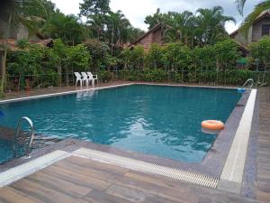 a large swimming pool with two chairs in a yard at BADAMI HERITAGE RESORT in Badami