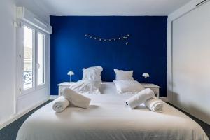 ein blaues Schlafzimmer mit einem großen weißen Bett mit zwei Kissen in der Unterkunft Charmant T3 climatisé proche Paris in Romainville