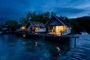 BesirHomestay taporaikos的夜间水面上的房子