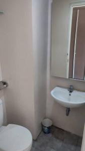 a bathroom with a white toilet and a sink at natural minimalist apt ice bsd in Cilandak