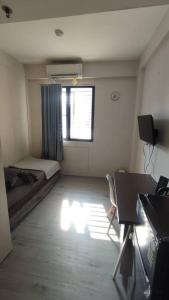 a room with a bed and a desk and a window at natural minimalist apt ice bsd in Cilandak