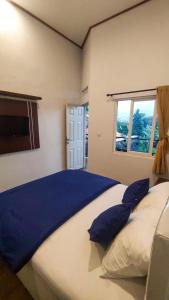 a bedroom with a large bed with blue pillows at Ayudia Camp & Coffee in Bedugul