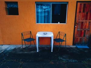 a white table and two chairs in front of a building at Saqua Beach Hostel in Saquarema