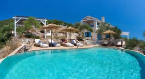 a swimming pool with chairs and umbrellas next to a house at Heliopetra Luxury Villa Lefkas in Vasiliki