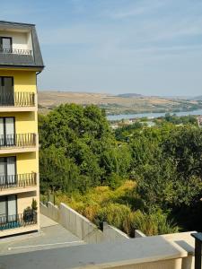 a yellow apartment building with a balcony and trees at Adam Home Ap in Fălticeni