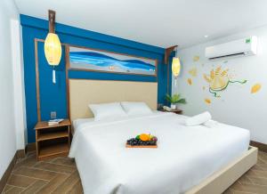 a bedroom with a large white bed with a bowl of fruit on it at Sujet Hotel Da Nang in Danang