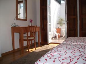 a bedroom with a desk and a bed and a table at Guesthouse Muralhas do Mino in Monção