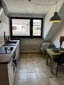 eine Küche mit einem Waschbecken, einem Tisch und einem Fenster in der Unterkunft Schöne DG - Wohnung in Bonn in Bonn