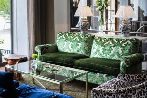 
a green couch sitting in a living room next to a window at Varbergs Stadshotell & Asia Spa in Varberg
