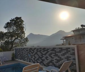 ein Pool mit Liegestühlen und Blick auf die Berge in der Unterkunft Casa Vista Baepi - Estilo Boho, Mais Streaming a 1,5km da Balsa in Ilhabela