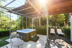 a hot tub under a pergola with two chairs at Hotel Laguna Deluxe - Terme Krka in Strunjan